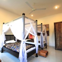Bedroom with two large single beds with mosquito nets.