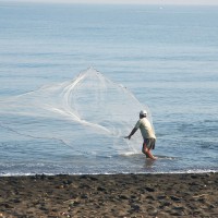 Man with fishing net on beach in Bali.