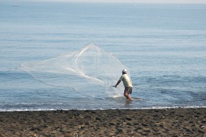 Man with fishing net on beach in Bali.